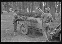 White migrant strawberry picker unloading automobile cushion springs from trailer. These will be used as bed springs. Hammond, Louisiana by Russell Lee