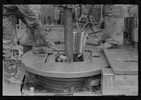 [Untitled photo, possibly related to: Removing clamps from rotary tacle before lifting out drilling pipe, oil well, Kilgore, Texas] by Russell Lee