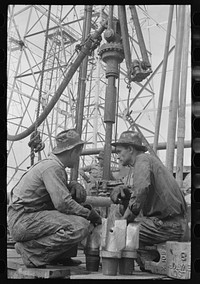 [Untitled photo, possibly related to: Oil drillers talking with bits in front of them and drilling equipment in background, Kilgore, Texas] by Russell Lee