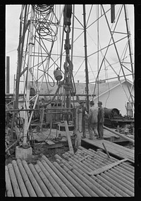 Detail of derrick showing traveling block, kelly joint, rotary table and lengths of drill pipe, Kilgore, Texas by Russell Lee