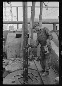 Oil field worker applying grease to drill stem, oil well, Kilgore, Texas by Russell Lee