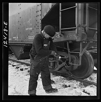 [Untitled photo, possibly related to: Chicago, Illinois. Workmen inspecting a journal box of a train in a Chicago and Northwestern Railroad departure yard]. Sourced from the Library of Congress.