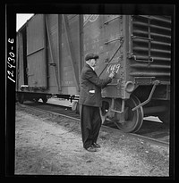 [Untitled photo, possibly related to: Chicago, Illinois. Car checker writing instructions in chalk for special handling of cars going over the hump at a Chicago and Northwestern Railroad yard]. Sourced from the Library of Congress.
