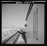 Freight train operations on the Chicago and Northwestern Railroad between Chicago and Clinton, Iowa. After a short wait to let a passenger train go by, the train starts up again and the rear brakeman gives his OK signal as he hops on the caboose. Sourced from the Library of Congress.
