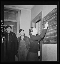 Clinton, Iowa. Miss Lucille Disher, whose father was a railroad worker for forty years, runs a rooming house for railroad workers. Here she is assigning rooms to a crew that just came in. The men's names on the board enable the "caller" to find and wake them in the morning. Sourced from the Library of Congress.