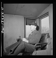[Untitled photo, possibly related to: Rear brakeman George Clark having his lunch in the cupola of the caboose on the Atchison, Topeka, and Santa Fe Railroad, between Marceline, Missouri and Argentine, Kansas. The bottle contains hot coffee]. Sourced from the Library of Congress.