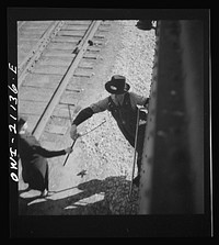 Dalies, New Mexico. Conductor C.W. Tevis picking up a message from a woman operator on the Atchison, Topeka and Santa Fe Railroad between Belen and Gallup, New Mexico. Sourced from the Library of Congress.