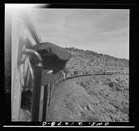[Untitled photo, possibly related to: Williams (vicinity), Arizona. A train on the Atchison, Topeka and Santa Fe Railroad between Winslow and Seligman, Arizona coming out of a tunnel through the hillside]. Sourced from the Library of Congress.