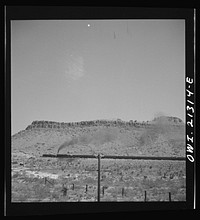 Kingman (vicinity), Arizona. A double-header eastbound passenger train on the Atchison, Topeka and Santa Fe Railroad between Seligman, Arizona and Needles, California, climbing a mountain. Sourced from the Library of Congress.