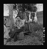 Migrant laborer, Canal Point, Florida. He is sitting on a bean hamper, which they call "muck-rockers.". Sourced from the Library of Congress.
