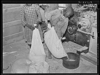Boy pouring his corn for grinding into meal at cooperative grist mill. Gee's Bend, Alabama. Sourced from the Library of Congress.