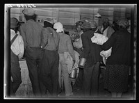  day laborers brought in truck from nearby towns, waiting to be paid off for cotton picking and buy supplies inside plantation store on Friday night. Marcella Plantation. Mississippi Delta. Mississippi. Sourced from the Library of Congress.