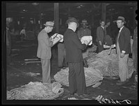 Bookmen for the warehouse follow the sale and check the prices of tobacco after the auction. Durham, North Carolina. Sourced from the Library of Congress.