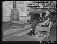 Mr. R.B. Whitley visiting in his general store. He is president of the bank and practically owns and runs the town. He is a big landowner, owns Whitley-Davis Farm and a cotton mill in Clayton. He said he cut down the trees and pulled up the stumps in that town of Wendell. Wake County, North Carolina. Sourced from the Library of Congress.