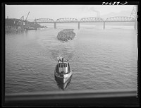 Log rafts are towed by tugs in the Willamette River. Portland, Oregon by Russell Lee