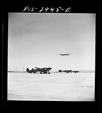 "Buzzing" the field. Member of interceptor squadron swoops low over parked airplanes to stimulate a strafing attack on an airport. Lake Muroc, California by Russell Lee