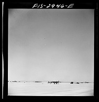 [Untitled photo, possibly related to: "Buzzing" the field. Member of interceptor squadron swoops low over parked airplanes to stimulate a strafing attack on an airport. Lake Muroc, California] by Russell Lee