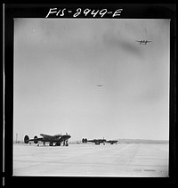 [Untitled photo, possibly related to: "Buzzing" the field. Member of interceptor squadron swoops low over parked airplanes to stimulate a strafing attack on an airport. Lake Muroc, California] by Russell Lee