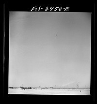 [Untitled photo, possibly related to: "Buzzing" the field. Member of interceptor squadron swoops low over parked airplanes to stimulate a strafing attack on an airport. Lake Muroc, California] by Russell Lee