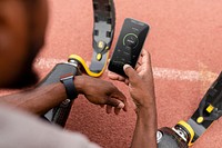 iPhone psd mockup with fitness tracker being held by an athlete with prosthetic legs on a running track