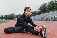 Woman warming up by stretching on a running track 