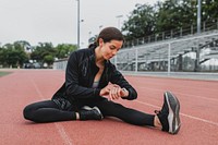 Woman warming up by stretching on a running track 