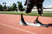 Athlete with prosthetic legs on sprint starting block 