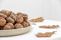 Free walnuts on plate, white table public domain CC0 photo.