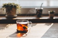 Free hot tea bag on wooden table under sunlight photo, public domain beverage CC0 image.