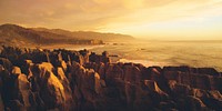 Panaroma of pancake rocks in the scenic view of mountains, beach and sunset.
