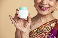 Indian woman in a traditional saree holding a skin care cream container mockup