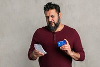 Stressed senior Indian man holding his bills and credit card 