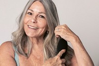 Cheeful senior woman brushing her hair