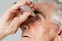 Closeup senior man applying eye drops 
