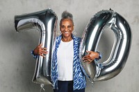 Cheerful senior woman holding silver balloons for her 70th birthday celebration