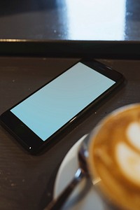 Mobile phone mockup by a coffee cup