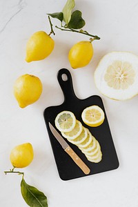 Fresh slices of lemon on a black chopping board flatlay