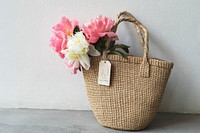 Woman carrying peonies in a wicker bag