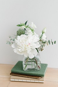 White flower bouquet in a cleared vase on a stack of books