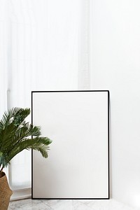 Blank black frame mockup by palm leaves