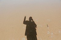 Calm waters over the sand with a shadow of a man