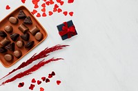 Chocolates on a tray by paper hearts 
