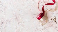 Rolls of ribbon on a pink marble background