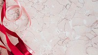 Rolls of red ribbon on a pink marble background