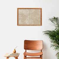 Picture frame mockup hanging above a classic wooden chair