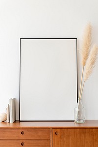 Blank large frame on a wooden sideboard in a living room