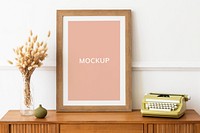 Picture frame mockup on a wooden sideboard table by a typewriter