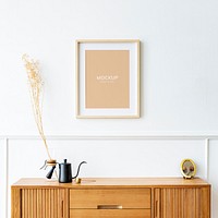 Picture frame mockup over a wooden sideboard table with dried flowers in a pour over glass 