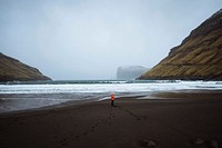 Woman in an orange windbreaker at Tj&oslash;rnuv&iacute;k beach in the Faroe Islands