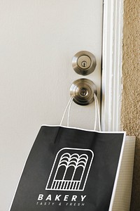 Contactless delivery bakery paper bag mockup hanging on a doorknob during the coronavirus pandemic